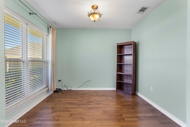 spare room featuring a textured ceiling and dark hardwood / wood-style floors