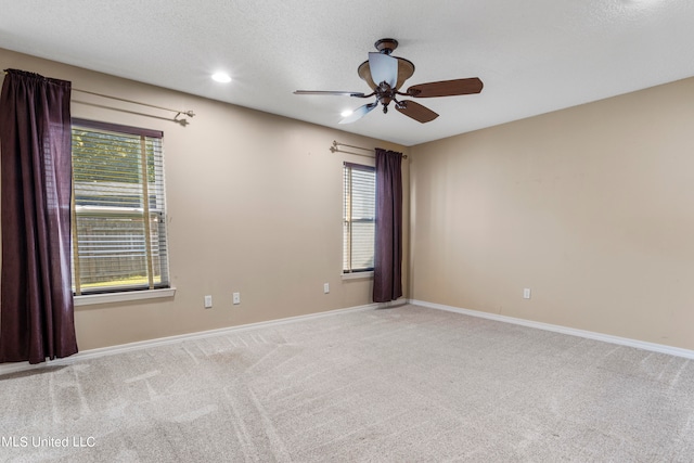 carpeted empty room with a textured ceiling, plenty of natural light, and ceiling fan