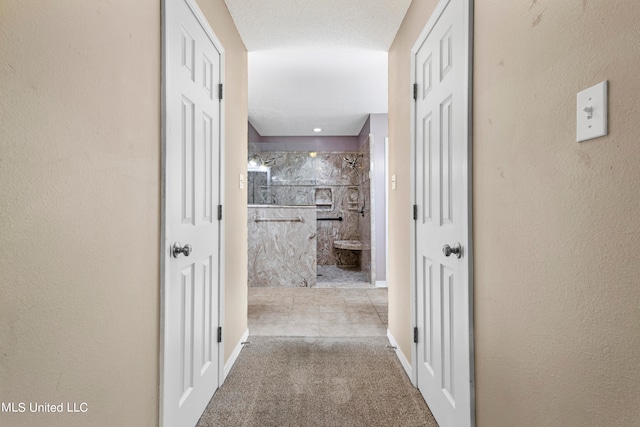 hallway with light carpet and a textured ceiling