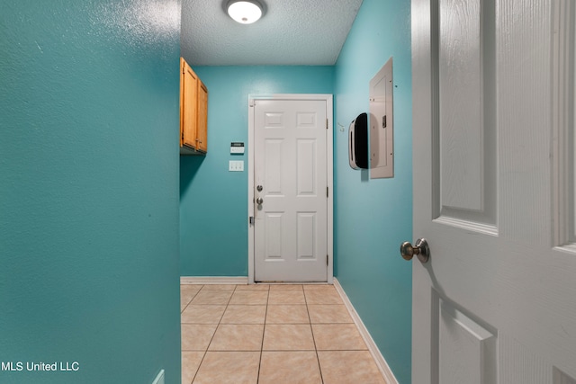 entryway with electric panel, a textured ceiling, and light tile patterned floors