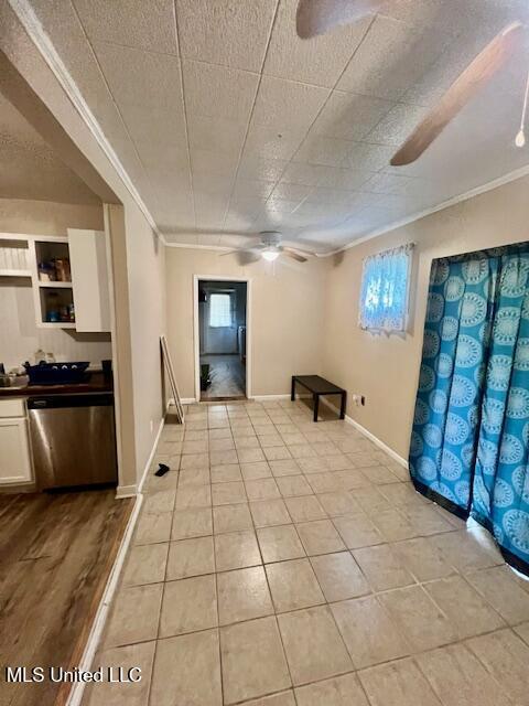 interior space with ceiling fan, baseboards, ornamental molding, and light tile patterned flooring