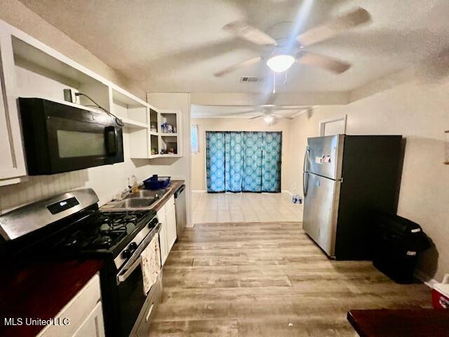 kitchen featuring light wood-type flooring, appliances with stainless steel finishes, a ceiling fan, and a sink