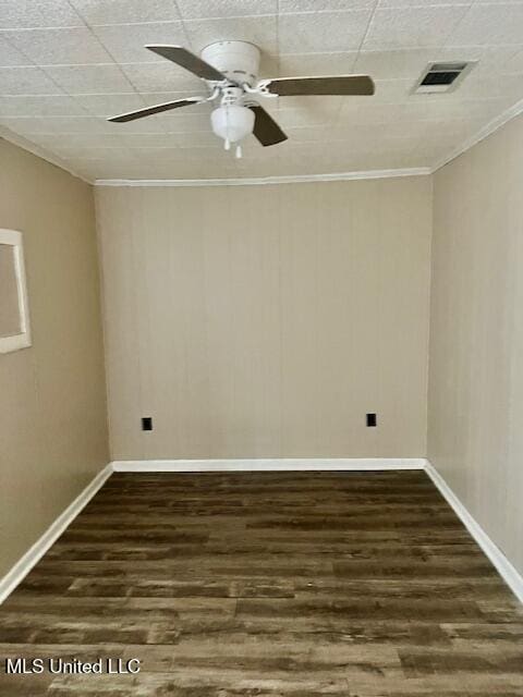 empty room with dark wood finished floors, visible vents, crown molding, and a ceiling fan