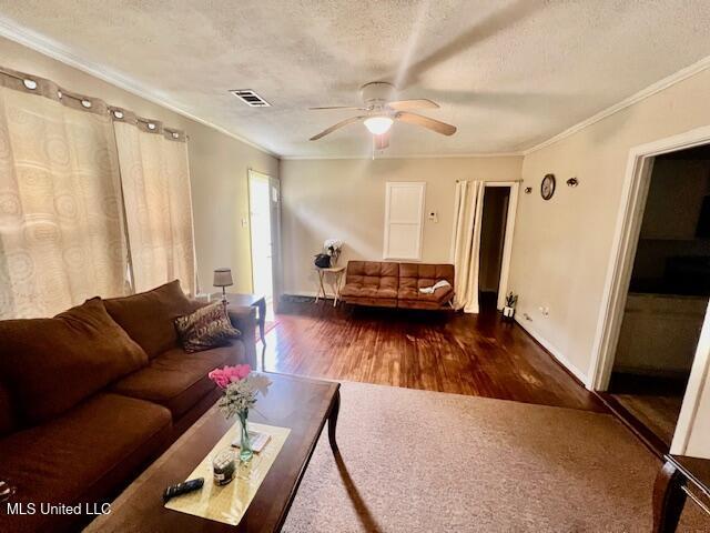 living room with visible vents, ceiling fan, wood finished floors, and ornamental molding