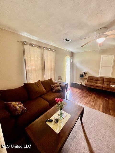 living area featuring ceiling fan, a textured ceiling, wood finished floors, and ornamental molding