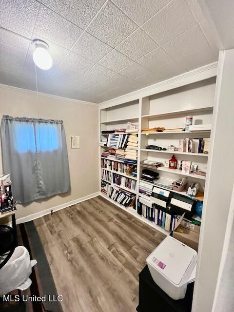 interior space with baseboards, crown molding, and wood finished floors