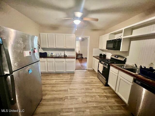 kitchen with light wood finished floors, open shelves, dark countertops, appliances with stainless steel finishes, and ceiling fan