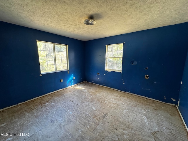 empty room featuring a textured ceiling and a healthy amount of sunlight