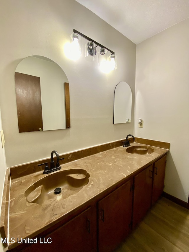 bathroom with double vanity, a sink, and wood finished floors