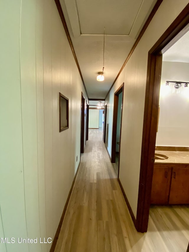 hall featuring ornamental molding, attic access, and light wood-style floors