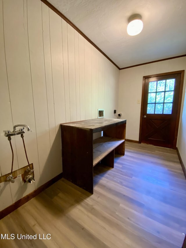 interior space featuring crown molding, light wood-style flooring, and baseboards