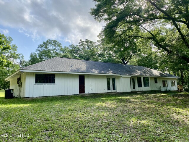 back of property with french doors, central air condition unit, and a lawn