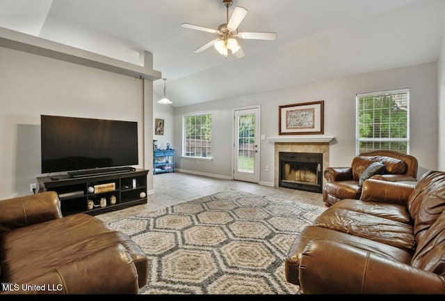 living area with lofted ceiling, ceiling fan, baseboards, and a tile fireplace