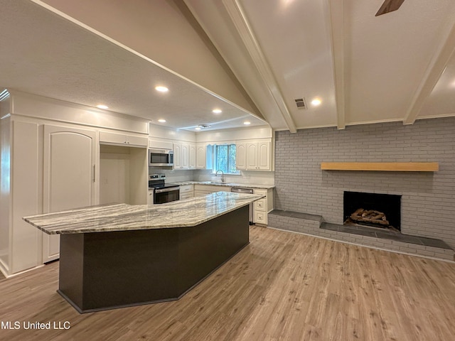 kitchen featuring sink, light stone countertops, light wood-type flooring, white cabinetry, and appliances with stainless steel finishes