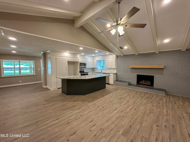 kitchen featuring a kitchen island, stainless steel appliances, hardwood / wood-style floors, lofted ceiling with beams, and white cabinets