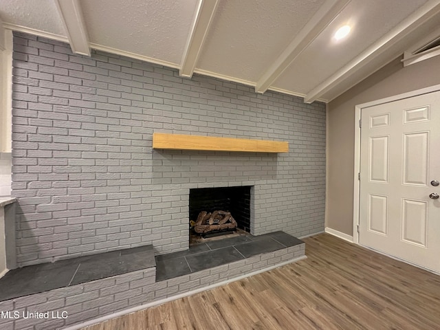 unfurnished living room with vaulted ceiling with beams, dark hardwood / wood-style floors, brick wall, and a fireplace