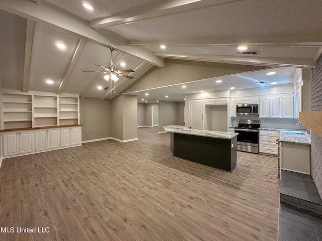 kitchen with white cabinets, appliances with stainless steel finishes, vaulted ceiling with beams, light hardwood / wood-style flooring, and a center island