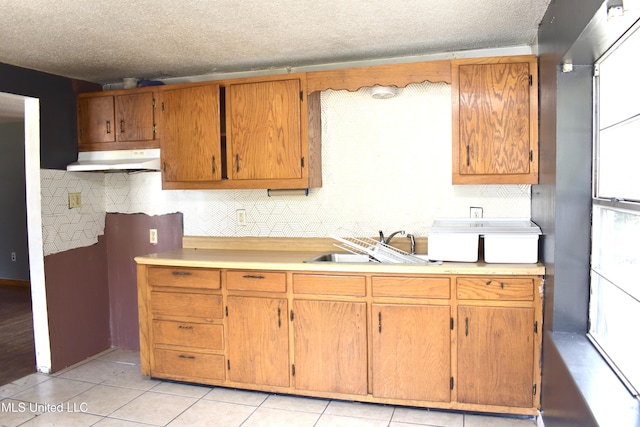 2201 15th Ave, Gulfport, MS 39501 - kitchen featuring under cabinet range hood, light countertops, tasteful backsplash, light tile patterned floors, and a textured ceiling