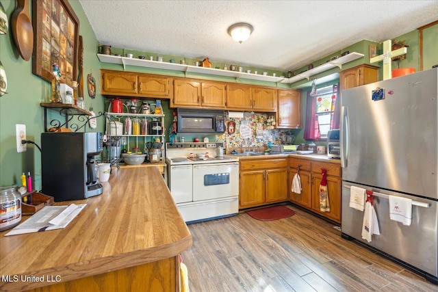 kitchen featuring a textured ceiling, light wood-type flooring, range with two ovens, and stainless steel refrigerator