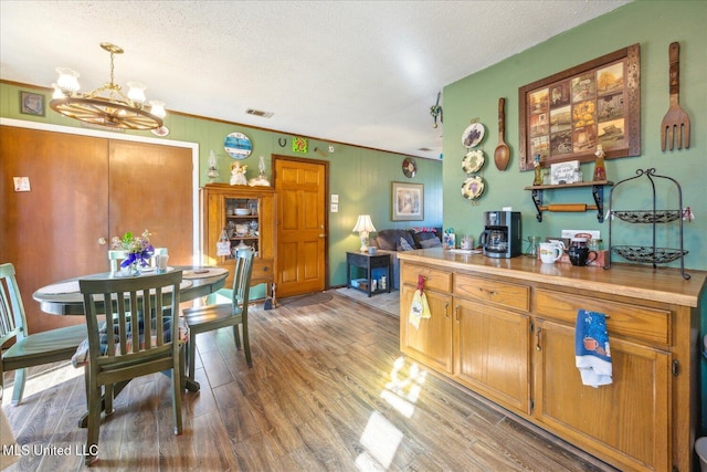 kitchen with decorative light fixtures, hardwood / wood-style floors, a textured ceiling, ornamental molding, and a chandelier