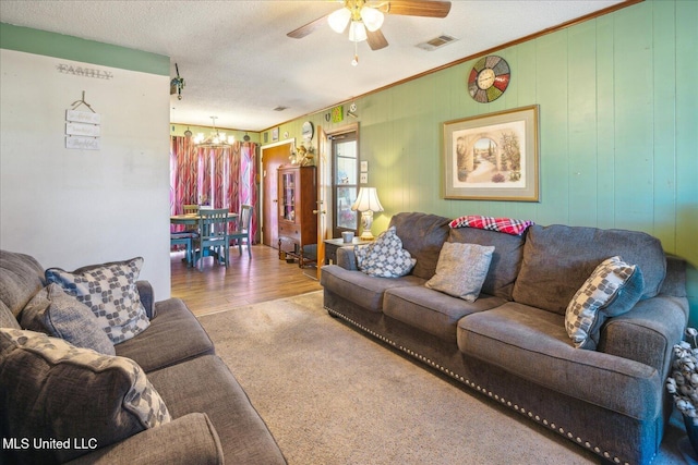 living room with ceiling fan with notable chandelier, a textured ceiling, and carpet flooring