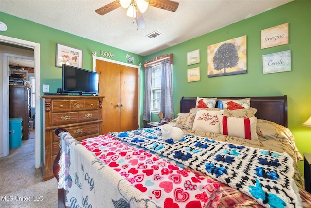 bedroom featuring ceiling fan, light colored carpet, a textured ceiling, and a closet