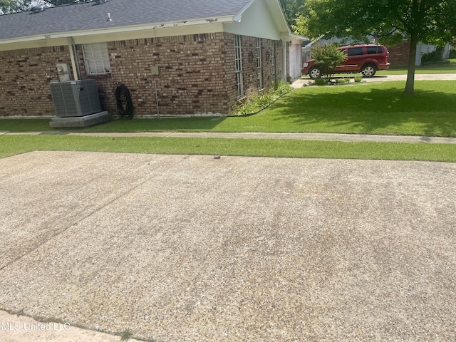 2909 Pimlico Dr, Ocean Springs, MS 39564 - view of side of home with central air condition unit, a garage, brick siding, a lawn, and a shingled roof