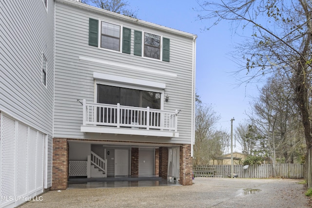 view of front of property with brick siding, driveway, and fence