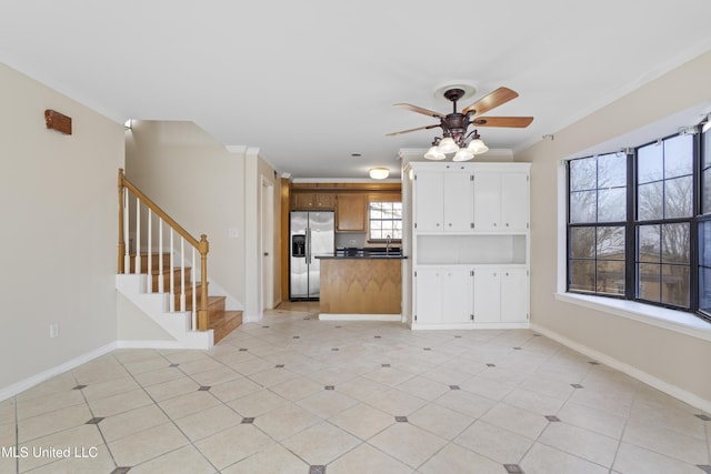 kitchen with ornamental molding, a ceiling fan, open floor plan, stainless steel fridge with ice dispenser, and baseboards