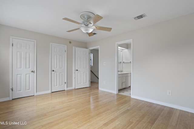 unfurnished bedroom with visible vents, baseboards, light wood-style flooring, multiple closets, and ensuite bathroom