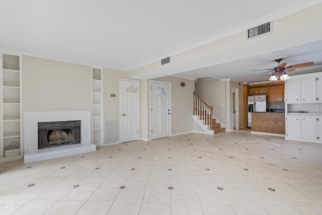 unfurnished living room featuring ceiling fan, a brick fireplace, visible vents, and ornamental molding