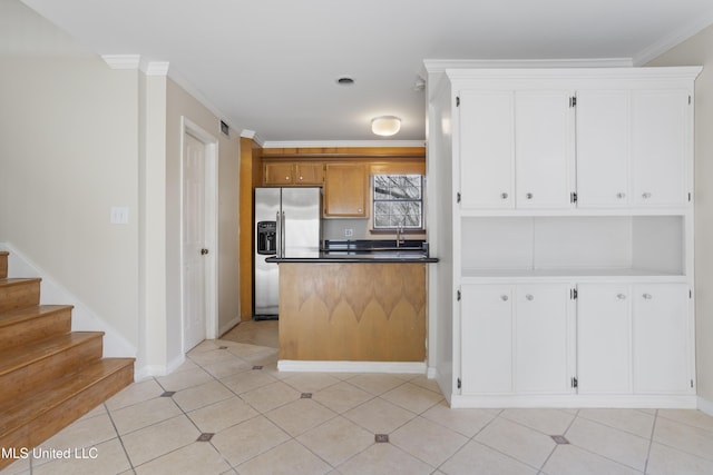 kitchen with dark countertops, white cabinets, stainless steel refrigerator with ice dispenser, and ornamental molding