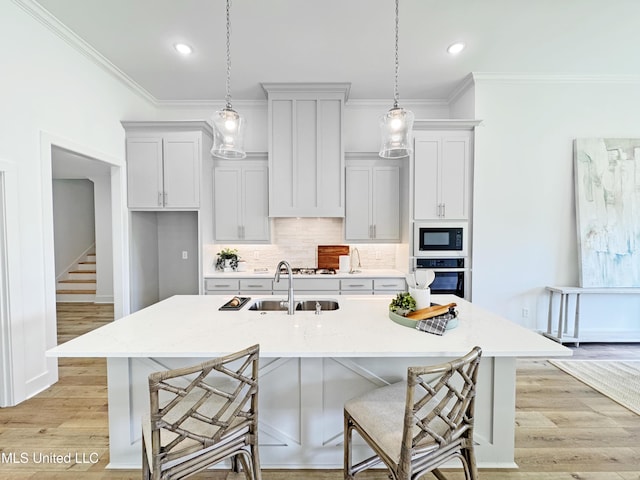 kitchen with black microwave, wall oven, a sink, and crown molding