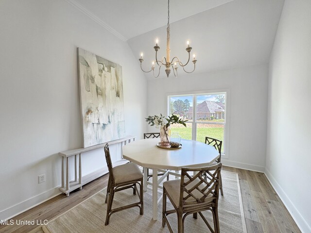 dining room featuring lofted ceiling, ornamental molding, a chandelier, and light wood-type flooring