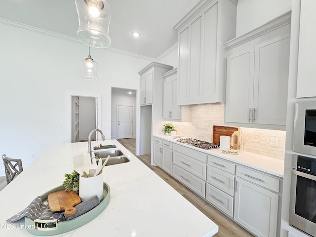 kitchen with crown molding, a sink, light wood-type flooring, stainless steel appliances, and backsplash