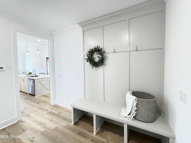 mudroom with light wood-type flooring, baseboards, a sink, and crown molding