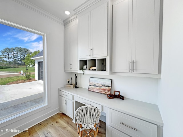 home office with recessed lighting, built in study area, ornamental molding, baseboards, and light wood-style flooring