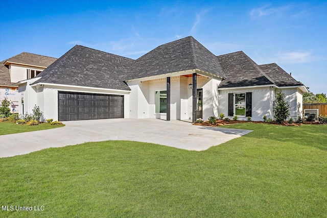 view of front of home featuring an attached garage, concrete driveway, a shingled roof, and a front yard