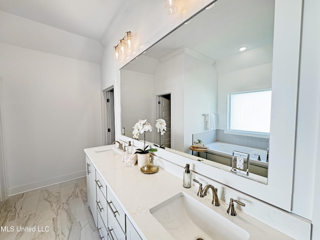 full bathroom with double vanity, marble finish floor, a bathing tub, and a sink