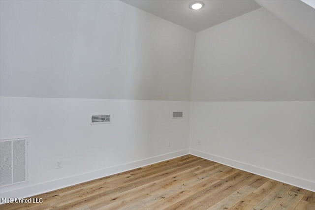 additional living space with vaulted ceiling, light wood finished floors, and visible vents