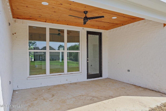 view of exterior entry with ceiling fan and a patio area