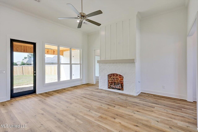 unfurnished living room featuring a brick fireplace, light wood-style flooring, baseboards, and crown molding