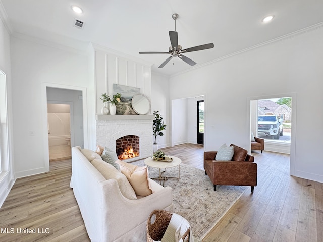 living area featuring ceiling fan, ornamental molding, light wood-style floors, and visible vents