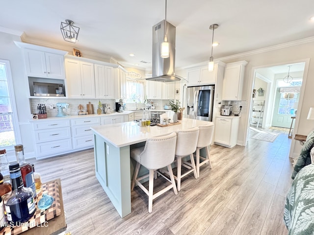 kitchen featuring stainless steel appliances, a center island, island range hood, and white cabinetry