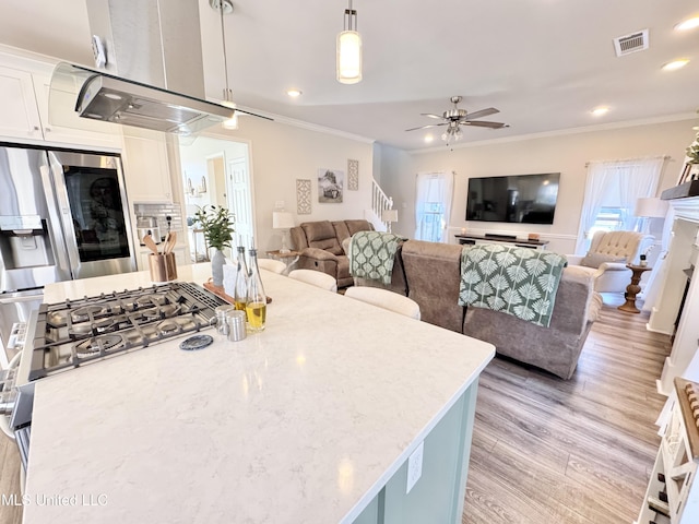 kitchen with ornamental molding, stainless steel fridge with ice dispenser, hanging light fixtures, and white cabinetry