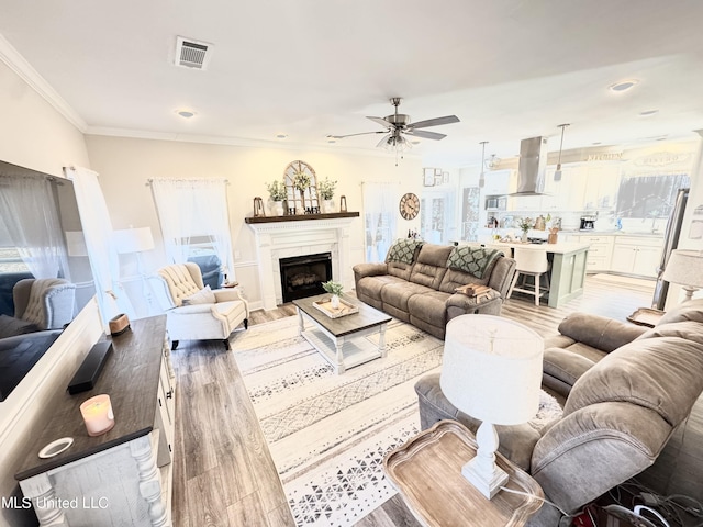 living room featuring light hardwood / wood-style floors, ceiling fan, and ornamental molding