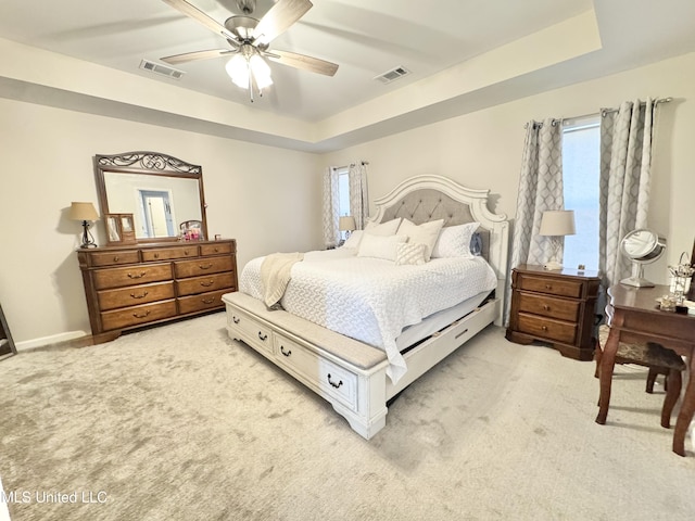 carpeted bedroom featuring a raised ceiling and ceiling fan