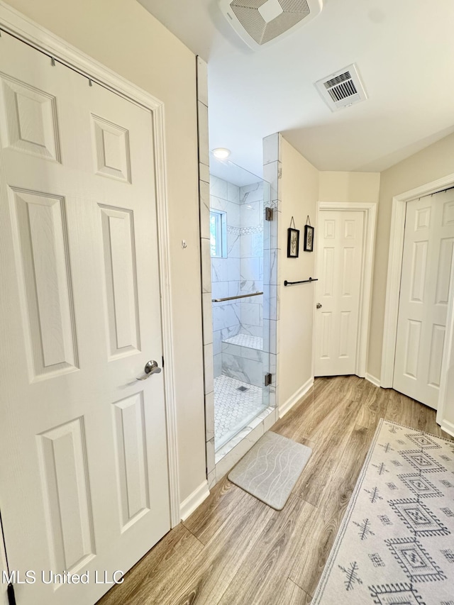 bathroom with hardwood / wood-style flooring and a shower with shower door