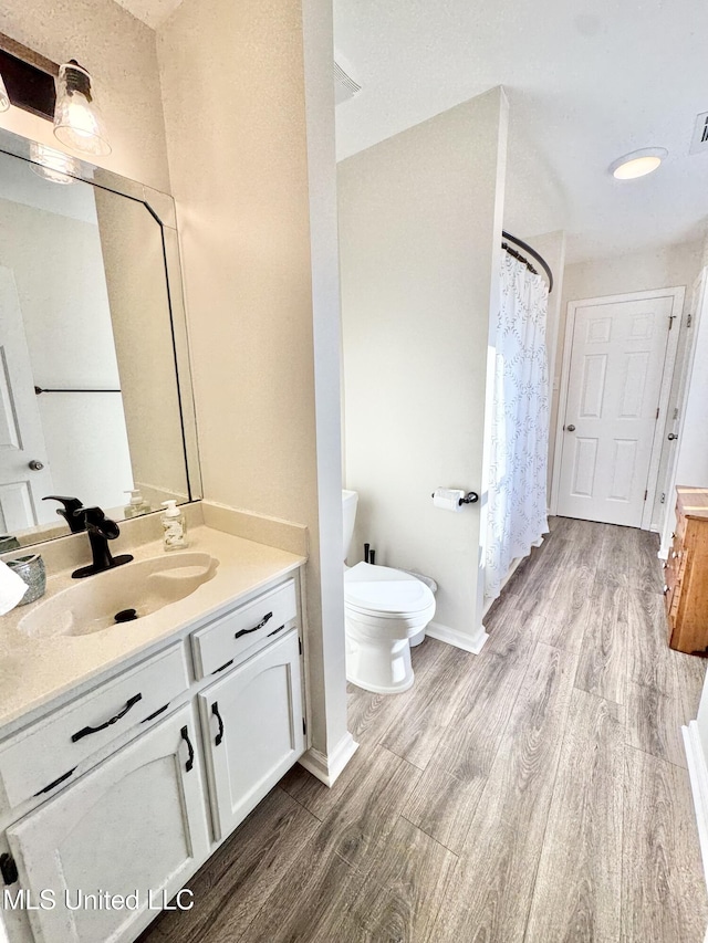 bathroom featuring a shower with shower curtain, hardwood / wood-style floors, vanity, and toilet