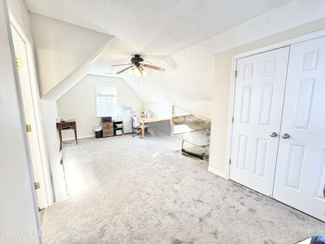 interior space featuring lofted ceiling, a textured ceiling, ceiling fan, and carpet